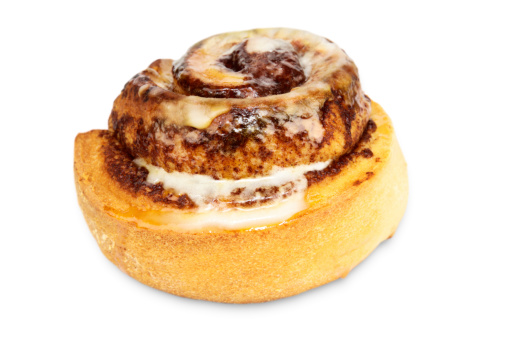 A delicious cinnamon bun sits isolated on a white background.