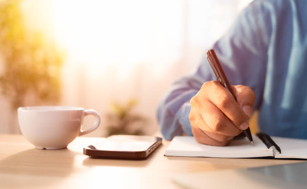 istock Close-up of man hand using writing pen memo on notebook paper or letter, diary on table desk office. Workplace for student, writer with copy space. business working and learning education concept. 1832968380
