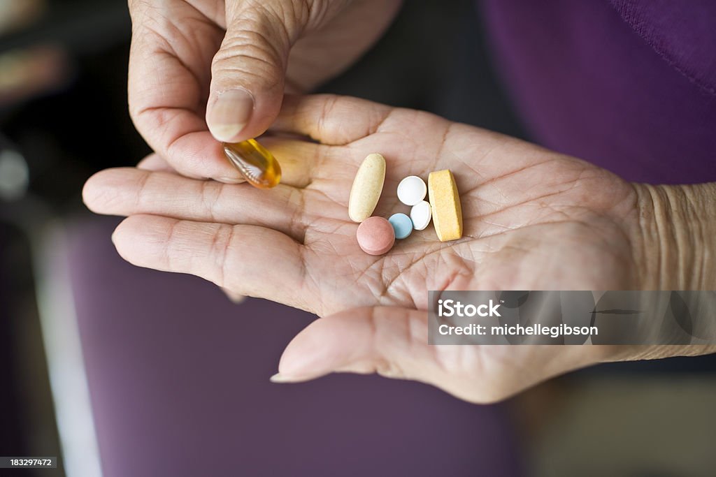 Medication Variety of vitamins and medication in the palm of an elderly senior woman Nutritional Supplement Stock Photo