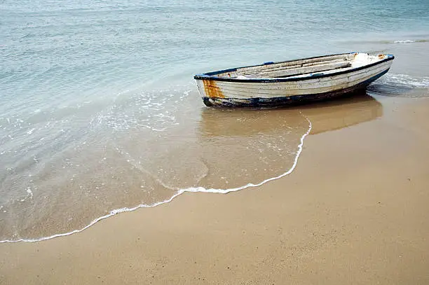 An abandoned rowing boat on a sandy beach