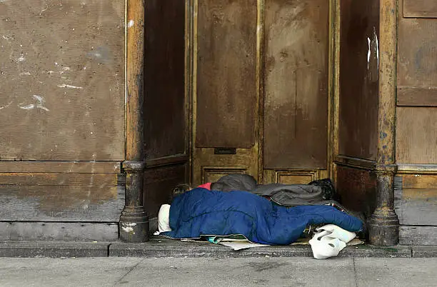 A homeless women sleeping in the entrance of an abondoned building.