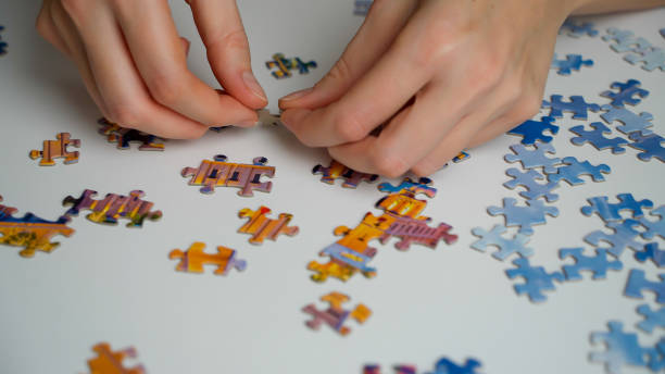 istock Close-up of well-groomed female hands assembling a desktop jigsaw puzzle 1832985983