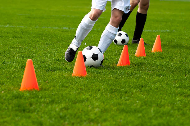 Soccer player running past red cones.
