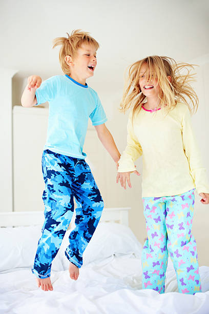 istock Cheerful young boy with his sister jumping on bed 183299416