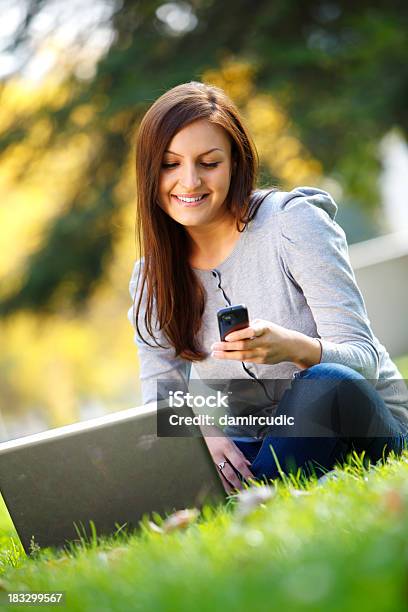 Giovane Donna Utilizzando Un Cellulare In Natura - Fotografie stock e altre immagini di 20-24 anni - 20-24 anni, Abbigliamento casual, Adulto