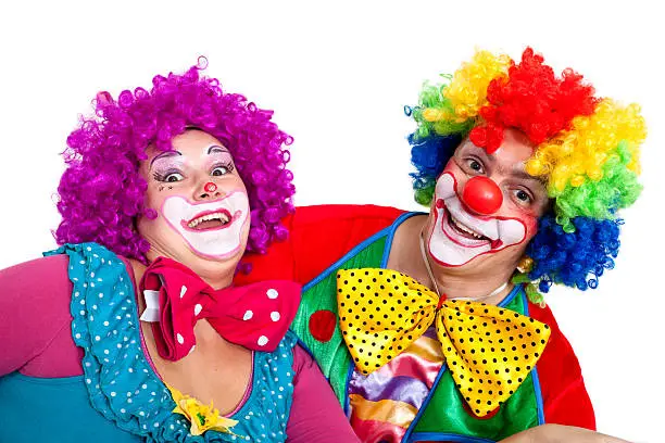 Two happy clowns smiling, making faces and looking at camera, white background.