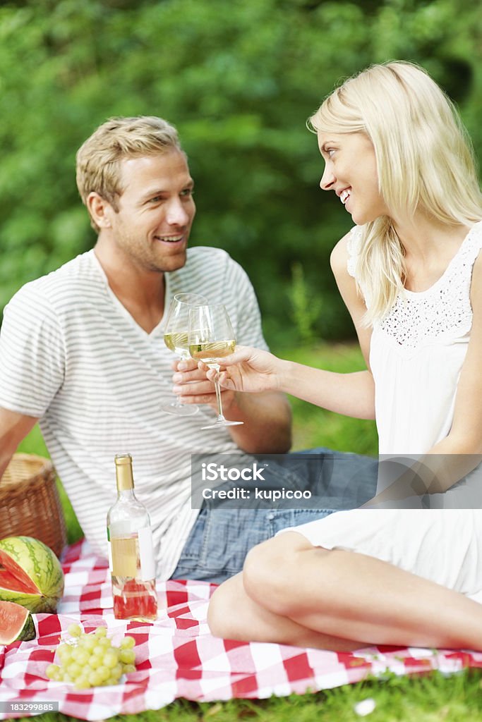 Coppia di innamorati Festeggia con champagne al picnic - Foto stock royalty-free di Abbigliamento casual
