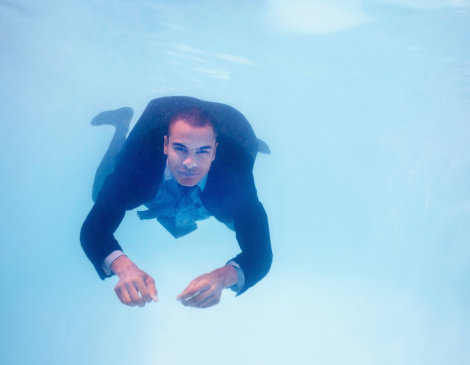 Photo of a business man getting refreshed under water in pool - copyspace