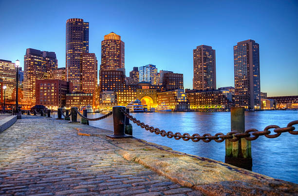 Boston Massachusetts Waterfront Boston harborwalk slightly processed using HDR technique. Photo taken along the waterfront at night in the South Boston southie neighborhood at night. The Boston cityscape is a mixture of old and new buildings. Boston is the capital and largest city in Masssachusetts. Boston is the largest city in New England  boston harbor stock pictures, royalty-free photos & images