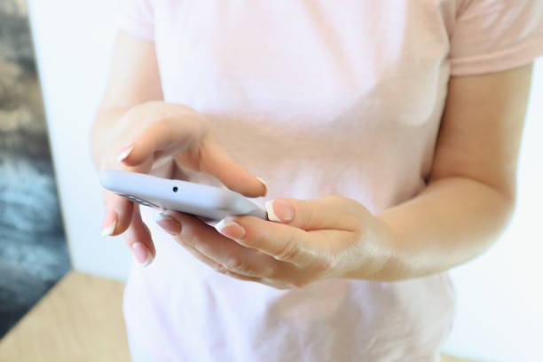 istock Woman hand using smartphone on light background. Woman using a Phone, close up view. 1833000448