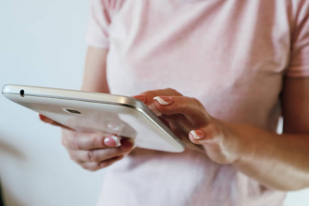 Closeup shot of a woman typing on digital tablet. Woman hand holding and point on electronic tablet PC. Concept of technology, connection, communication.