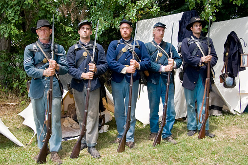 A group of American Civil War reenactors portraying Union soldiers standing at attention while being addressed by their commanding officer.