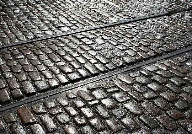 Sun shining on rain soaked Victorian street cobbled surface with railway/tram linesAn Victorian brick wall pattern: