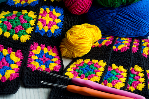 Crochet texture, thread rolls and hooks. Colorful cotton granny square. Hand knitted zigzag jewelry, a favorite hobby.