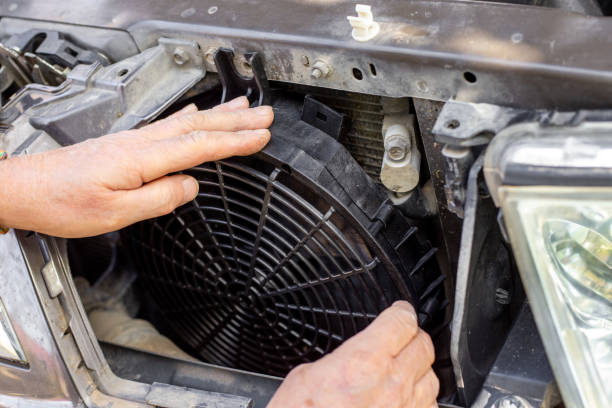 istock A man fixes an engine cooling fan under the radiator grill of a car. Machine maintenance and repair 1833005280