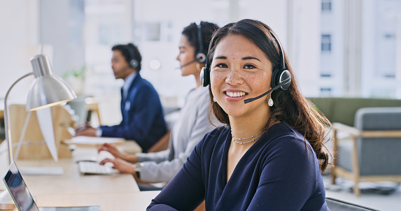 Call center woman, smile and portrait at help desk, job and staff group with computer, advice and office. Japanese agent, pc and microphone with headphones, consulting or listen for technical support