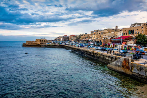 People walk on the waterfront in the Old City of Acre, Israel on a cloudy day.