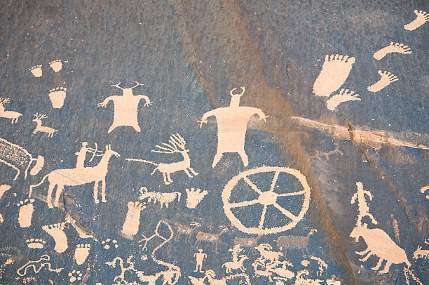 Cave Drawing with Hunters and Wheels "Cave drawing of animal scenes with hunters, footprints, and tools.Newspaper Rock in Utah." cave painting photos stock pictures, royalty-free photos & images