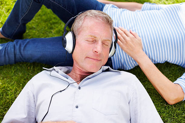istock Senior man listening to music while resting on woman's lap 183301619