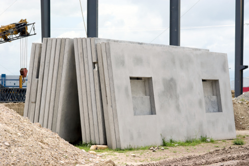 Prefabricated concrete walls with window openings at a construction site.