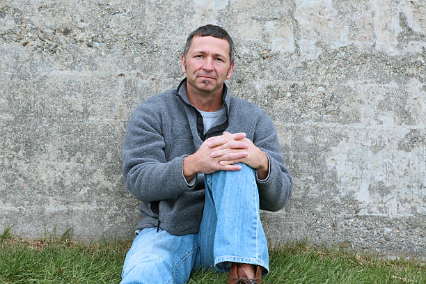 45 year old man alone sitting against a cement wall. These and more images in my portfolio