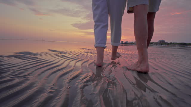 SLO MO TS Feet of a senior couple walking barefoot on the beach at sunset