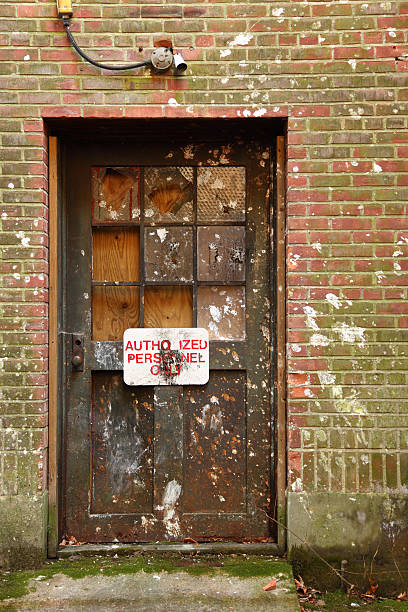 istock Old abandoned factory door with broken windows, deteriorating facade 183302846