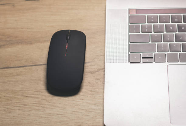 istock Black wireless minimalist mouse near the gray laptop . Modern technology device. 1833032074
