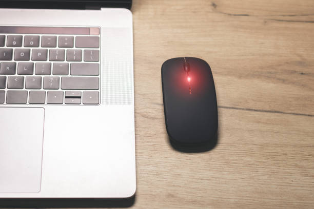 istock Black wireless minimalist mouse near the gray laptop . Modern technology device. 1833032078
