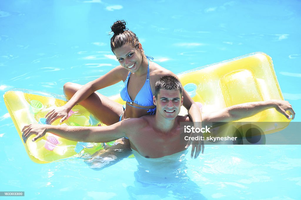 Sorridente coppia in piscina, guardando fotocamera. - Foto stock royalty-free di Abbracciare una persona
