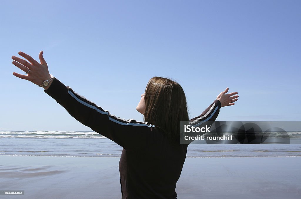 Arms Raised in Worship A young woman at the beach raising her arms in worship. Adult Stock Photo