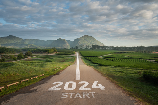 Happy new year 2024,2024 symbolizes the start of the new year. The letter start new year 2024 on the road in the nature fresh green tea farm mountain environment ecology or greenery wallpaper concept.