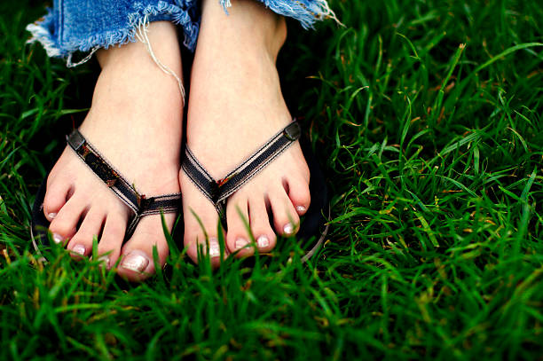 Feet in grass with sandals and cut off jeans.