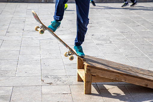 Close up view of sports legs standing on a skateboard. Riding on scateboard. Summer fun and leisure. Concept of extreme sport.