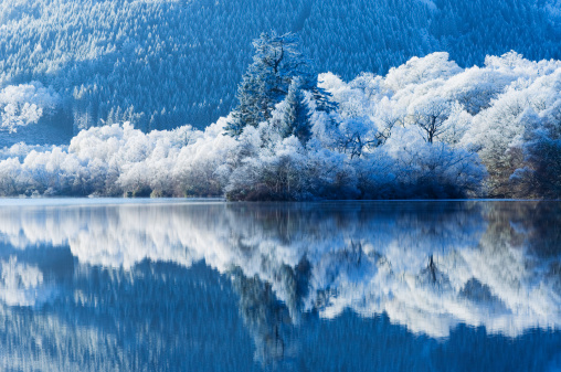 Picturesque landscape of a snowy winter mountain lake. Small lake next to the Saut Deth Pish waterfall during autumn and a snowy day, located in the Aran Valley, Pyrenees, Catalonia, Spain.