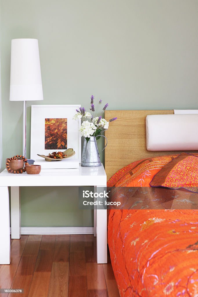 Dormitorio en la mesa de noche con lámpara de decoración y flores - Foto de stock de Cama libre de derechos