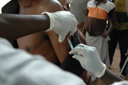 A Christian doctor gives a life saving shot in the arm to an African in his village.