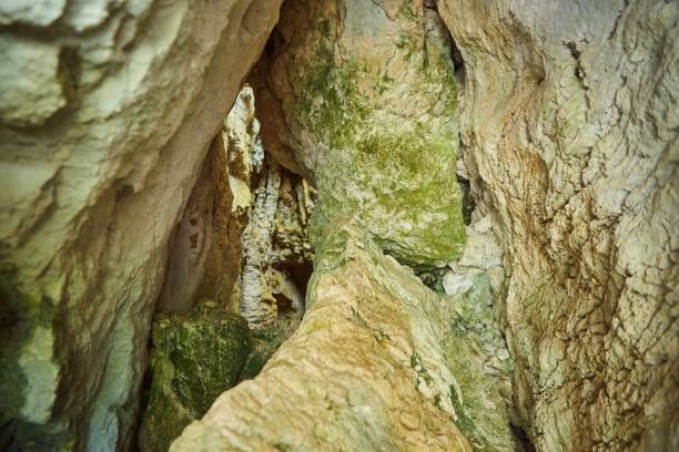 istock Dark cave view from inside with a lumen. Stalactites and stalagmites inside the stone grotto. Colorful stones in the cave. 1833068062