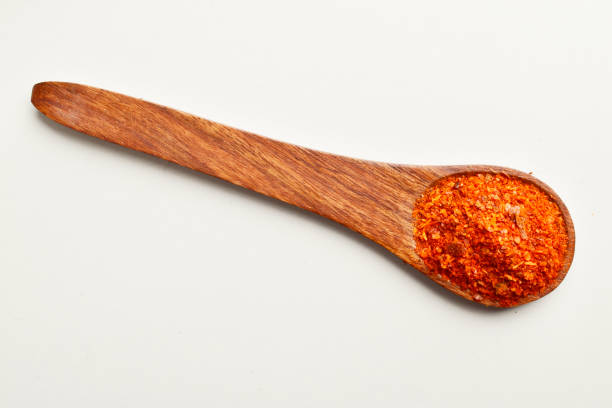 istock Ground red chilli in wooden spoon isolated on white background 1833078575