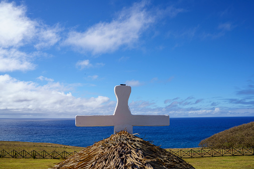 Wooden cross standing on the edge of a cliff with a dramatic sky backdrop  of Easter Island.