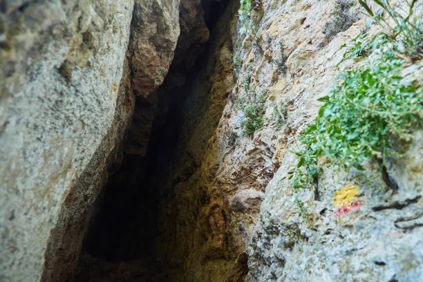 istock Dark cave view from inside with a lumen. Stalactites and stalagmites inside the stone grotto. Colorful stones in the cave. 1833083807