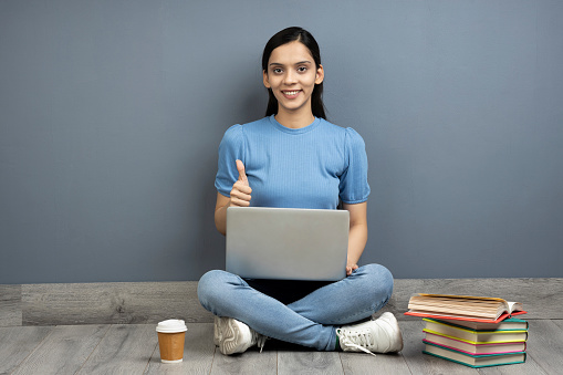 Photo of pretty girl using laptop on wooden floor