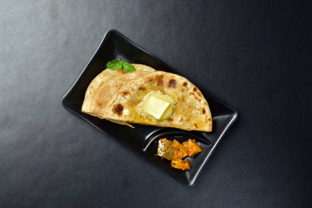 istock Sliced butter paratha with mango pickle on black background 1833088985