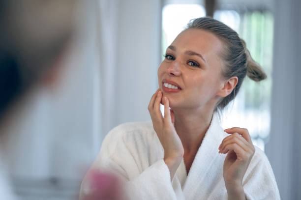 istock Young smiling woman applying cream on her face 1833089516