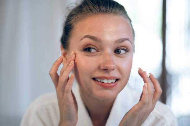 istock Young smiling woman applying cream on her face 1833089521