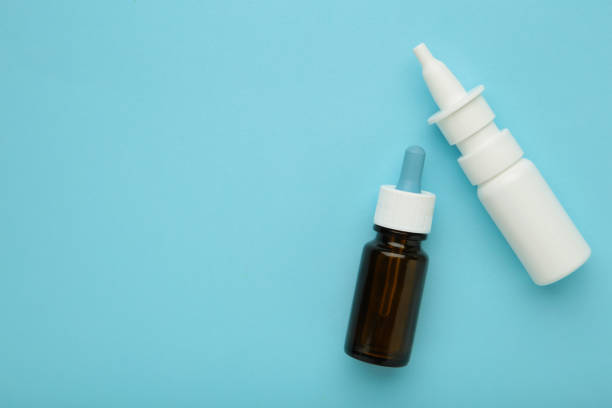 istock Bottles of nasal drops on blue background. Space for text 1833103668
