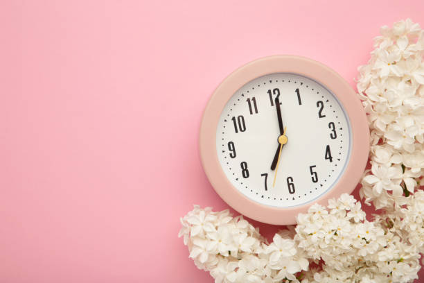 istock Clock alarm and lilac flowers on pink background. Environment concept. spring season. copy space. 1833105728
