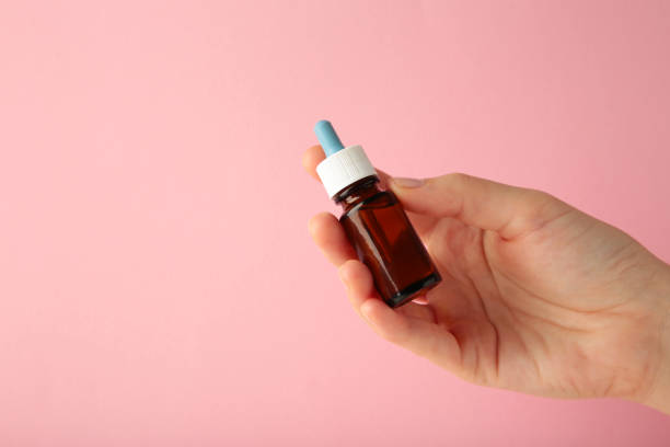 istock Hand holds a bottle of nasal drops on pink background. Space for text 1833107825