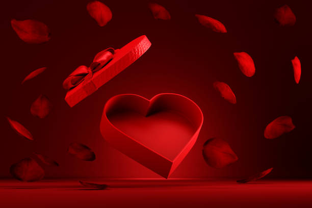 Heart shaped gift box with rose petals flying on red background.