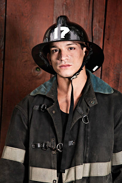 Young Firefighter in vintage uniform looking at camera in front of a wooden wall.See more of my Sutton-a-lypse photos: